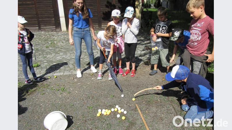 Kleiderbügel und Schirme dienen als Hilfsmittel, um die Bälle aus dem markierten Quadrat zu befördern, ohne darin den Boden zu berühren. Bild: sck