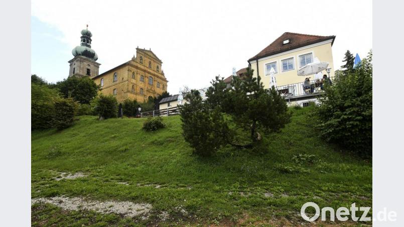 Der Neubau, der sich Richtung Kirche strecken wird, bleibt so flach und tief an den Hang geduckt – ohne diesen weiter als bisher abzugraben, wie der Bauherr versichert –, dass gar keine Chance bestehe, das Gotteshaus zu verdecken. Die alte Bergwirtschaft, die bis auf den neueren Anbau links äußerlich unverändert bleibt, tue das heute ja auch nicht. Bild: Petra Hartl