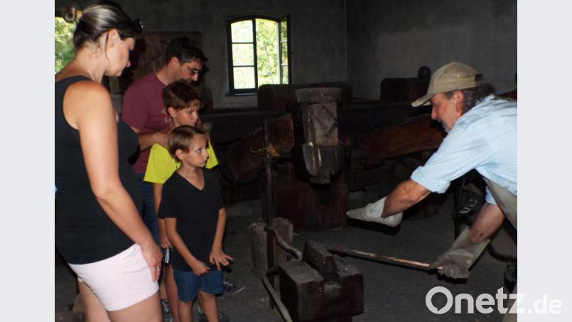 Schmied Georg Honig erläuterte den Besuchern ein maschinell betriebenes Hammerwerk, den sogenannten Schwanzhammer. Der war der verlängerte Arm des Schmiedes. Ein Stiel mit Holz, einem Hammerkopf aus Eisen und dem Hammerbär, einem fest verankerten Holzklotz, auf dem die Werkstücke lagen. Bild: e