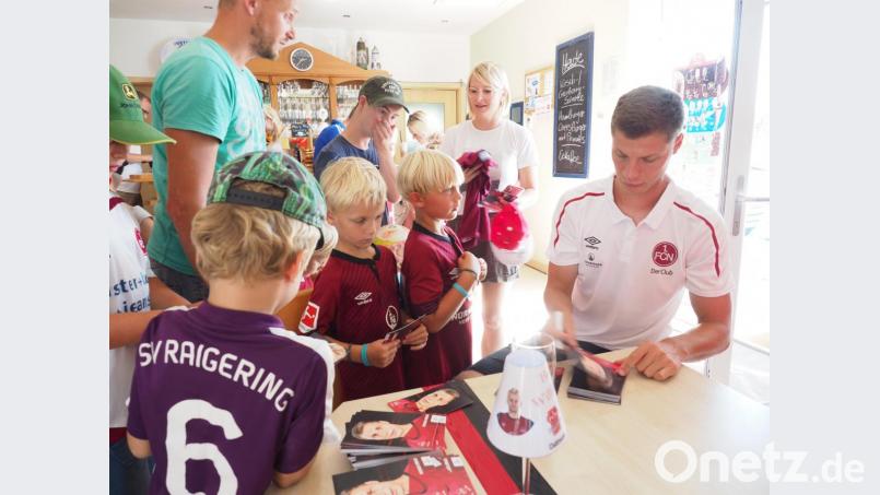 Clubprofi Patrick Erras schreibt fleißig Autogramme für die vielen kleinen Fans des 1. FC Nürnberg. Bild: ref
