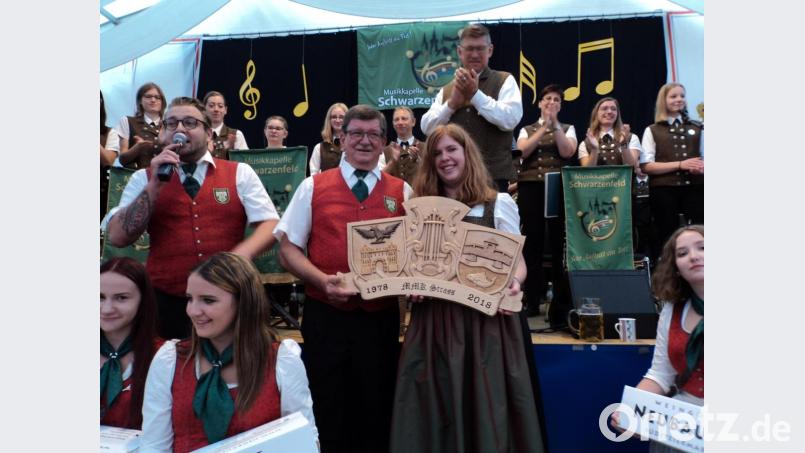 Als Gastgeschenk der Kapelle aus Straß gab es eine Holzschnitzerei von Herrmann Bohla mit den Motiven der beiden Musikkapellen. Bild: ksi