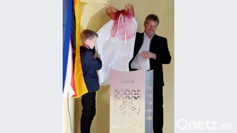 Dritter Bürgermeister Adolf Hammer packt mit Sohn Joseph das Jubiläumsgeschenk auf der Bühne aus. Es ist ein Feuerkorb mit dem Wappen der beiden Kommunen und der ungarischen Aufschrift: „Herzlichen Glückwunsch zu zehn Jahre Stadterhebung“. Bild: exb