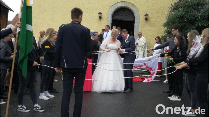 Die Landjugend Gaisthal überraschte das Brautpaar Julia und Thomas Sorgenfrei mit einem Spalier vor der St.-Wolfgang-Kirche in Schneeberg. Bild: Portner