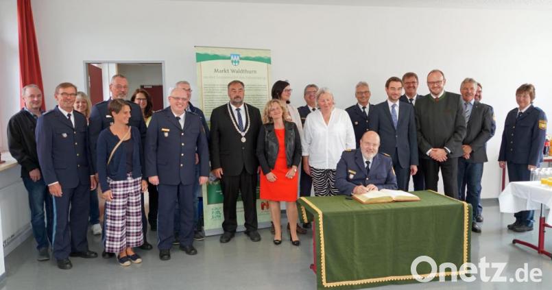 Polizeipräsident Norbert Zink (sitzend) trägt sich in das Goldene Buch der Marktgemeinde Waldthurn ein. Bild: fvo