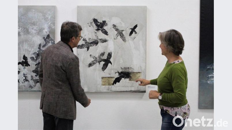 Berit Opelt (rechts) erklärt ihrem verwunderten Ehemann den Einsatz der Teebeutel auf &quot;Kolkraben&quot;. Ihre Vernissage &quot;Frakturen&quot; zeugt von Ästhetik und einer widersprüchlichen Ruhe resultierend aus der eingesetzten Mischtechnik. Bild: Dagmar Williamson