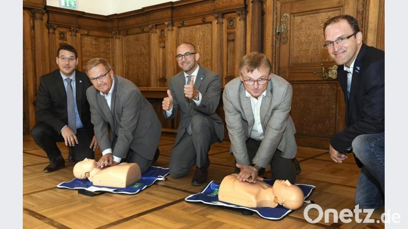 Bürgermeister Martin Preuß (Zweiter von links) und Klinikumsvorstand Manfred Wendl (Zweiter von rechts), zeigen wie’s geht: Die lebensrettende Reanimation will gelernt sein. Darum geht es bei der bundesweiten Woche der Wiederbelebung, wegen der auch Marc Bigalke (links), der Ärztliche Leiter der Zentralen Klinikums-Notaufnahme, Dr. Andreas Redel (Mitte) und Dr. Jens Schlör (rechts) ins Rathaus gekommen sind. Bild: Petra Hartl