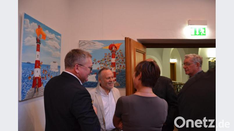 Künstler Adolf Ritz (Zweiter von links) vor seinen Leuchtturm-Bildern im Gespräch mit Oberbürgremeister Michael Cerny (links) und Besuchern der Ausstellung. Bild: inl