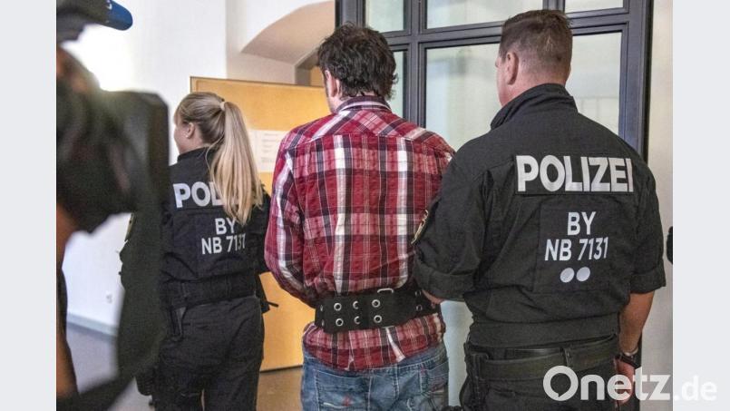 Der Angeklagte wird von Polizisten in den Verhandlungssaal des Landgerichts geführt. Bild: Armin Weigel/dpa