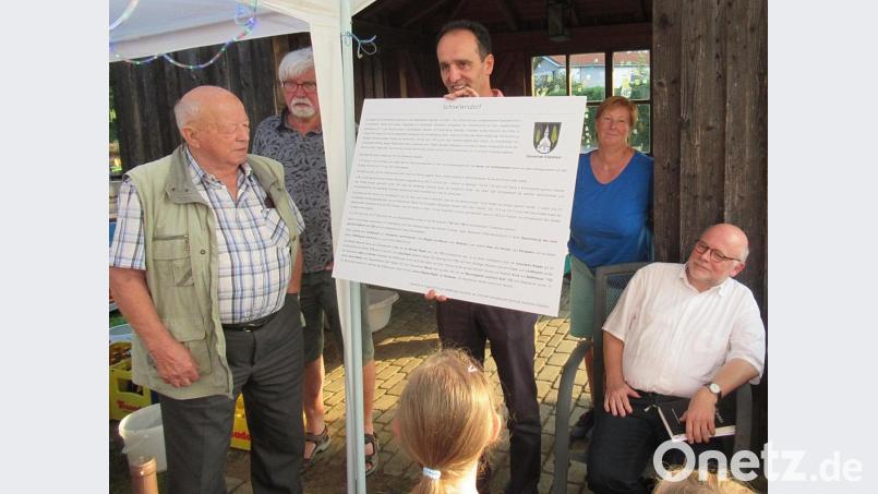 Bürgermeister Hans-Jürgen Strehl überreicht im Beisein von Pfarrer Matthias Ahnert die Gedenktafel, die am Bushäuschen in Schnellersdorf einen Platz gefunden hat. Bürger aus dem Ort verfolgten das Geschehen. Bild: gru