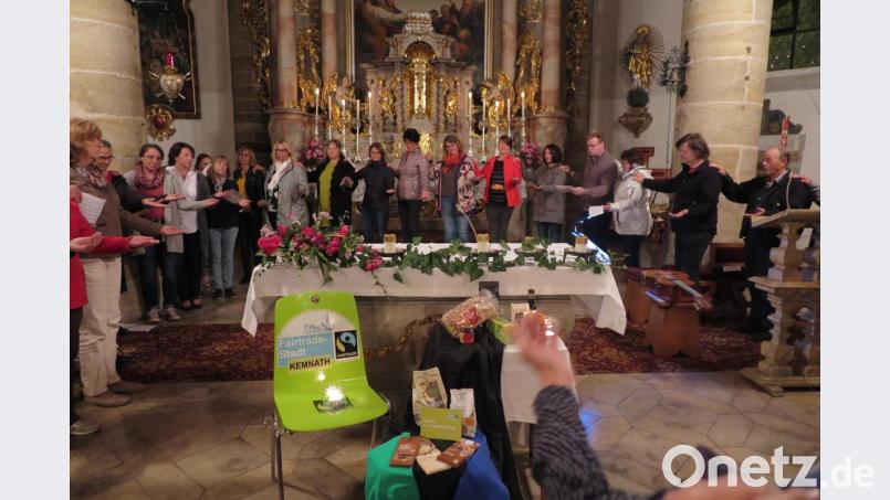 Beim Segenskreis hielt jeder die linke Hand geöffnet wie eine Schale. Die rechte Hand legte er behutsam auf die linke Schulter des rechten Nachbarn. So empfing jeder den Segen und gab ihn weiter. Vor dem Volksaltar waren fair gehandelte Waren aufgebaut. Bild: jzk