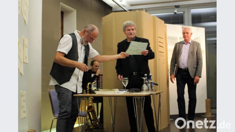 Friedrich Brandl (links) verteilt an Karl Krieg (Mitte) und Bernhard Setzwein (rechts) seine Notizen über das Jahr 1968. Professioneller Musiker Mike Reisinger trötet auf der Entenpfeife während er in seiner Jukebox-Attrappe, auch &quot;Kabuff&quot; genannt, verweilen muss. Bild: Dagmar Williamson, dwi
