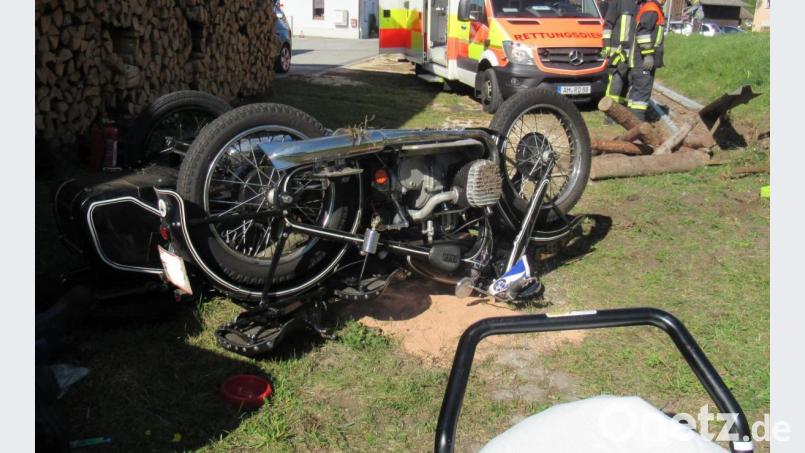 Von der Straße in den Vorgarten: Das Motorradgespann landete kopfüber zwischen Holz und Gartengeräten. Bild: pp