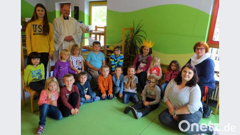 Leiterin Kerstin Dilling (rechts) und ihre Mitarbeiterinnen hatten mit den Kindern die Andacht mit Pfarrer Heribert Stretz (hinten, Zweiter von links) vorbereitet Bild: hl