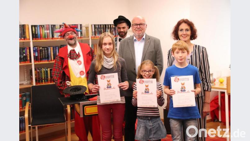 Sie haben allen Grund, stolz zu sein: Felix Kaufmann (vorne rechts) wird bei der Abschlussparty des Sommerferien-Leseclubs in der Stadtbibliothek für 38 gelesene Bücher ausgezeichnet, Anna Grädler (vorne links) für 36 und Lisa Lehnerer (vorne Mitte) für 26. Katharina Papp mit ebenfalls 26 Büchern fehlt auf dem Bild. Den Siegern gratulieren Bibliotheksleiterin Luise Eckert (hinten rechts), Bürgermeister Hans-Jürgen Reitzenstein (hinten, Zweiter von rechts), Jongleur Jonies Juggling (hinten, Dritter von rechts) und Zauberer Sirbas (hinten links). Bild: cog