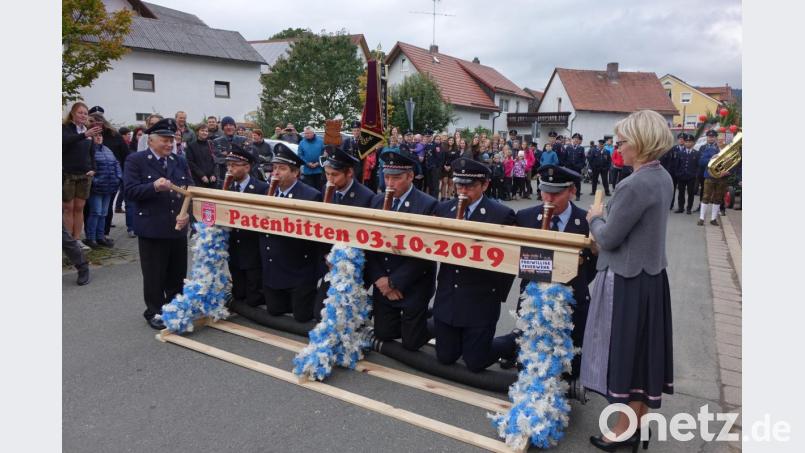 Mit ruhiger Hand führen Schirmherr Hans Wirnshofer (links) und Festmutter Gertraud Enk die Trinkvorrichtung für die gefüllten Gläser. Diese erste Aufgabe löst die Weidinger Feuerwehrführung mit Bravour. Bild: mmj