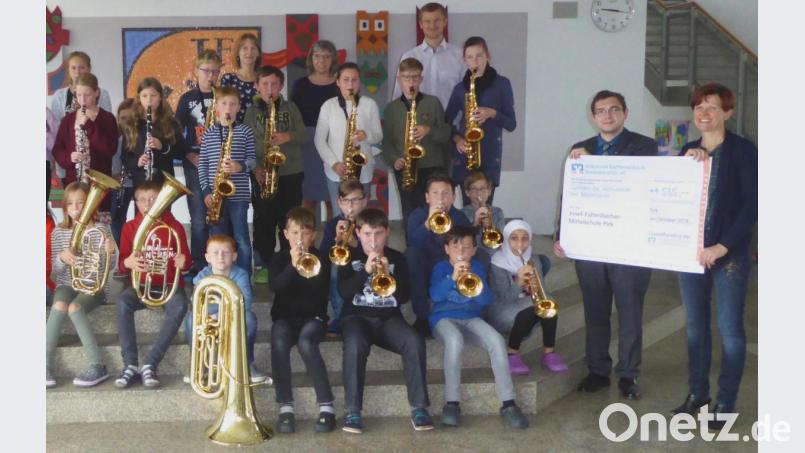 Die beiden Bläserklassen freuen sich über den Scheck in Höhe von 4 535 Euro zusammen mit Geschäftsstellenleiterin Reinhilde Ernst und stellvertretendem Schulleiter Mathias Werner (letzte Reihe rechts) sowie Berater Tobias Zapf und Klassenlehrerin Kerstin Kiener. Bild: Schönberger, Ferdinand [fsb]