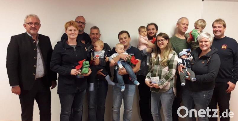 Bürgermeister Rudolf Schopper (links) und Vertreter der Feuerwehr begrüßen sieben kleine Püchersreuther und übergeben ihren Eltern Rauchmelder für die Kinderzimmer und schenken den Kleinen Plüschdrachen. Bild: hos