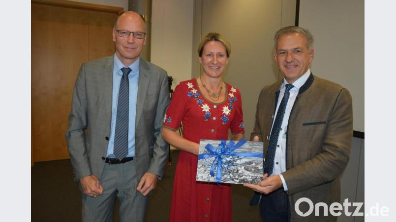 Mit einem alten Bild der Villa aus dem Jahr 1920 überraschte Bürgermeister Stefan Grillmeier (rechts) die neue Werksärztin Dr. Tatjana Wernicke. Mit im Bild Schott-Standortleiter Stefan Rosner. Bild: jr