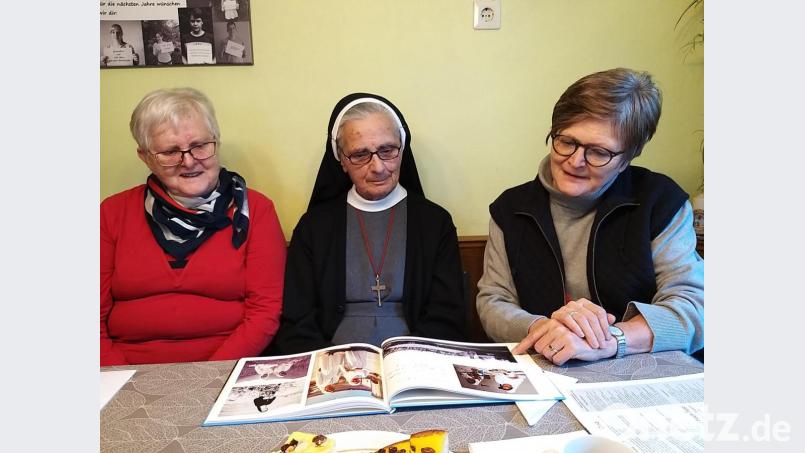 Die Missionarin und Ordensfrau,Anna Rita (Mitte) hat zu ihrer 50-jährigen Profess ein Fotobuch von ihrer Familie bekommen. Gern schauen ihre jüngere Schwester, Rita Haberkorn (li.) und Dr. Annemarie Schraml (re.) die alten Erinnerungen mit ihr an. Bild: ubb