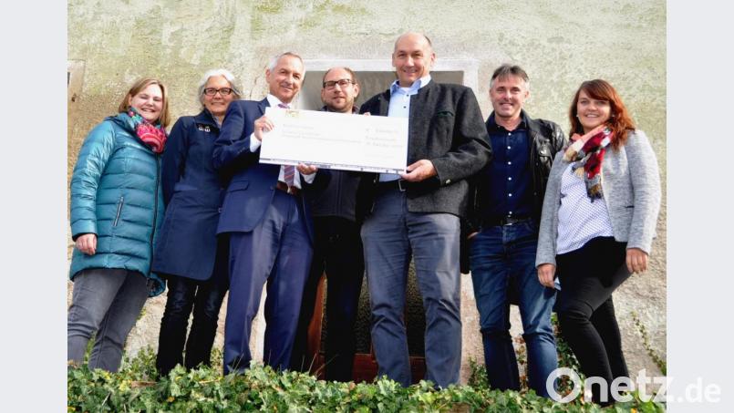 Große Freude bei Bürgermeister Max Völkl (Dritter von rechts), der von Behördenleiter Thomas Gollwitzer vom Amt für Landliche Entwicklung (Dritter von links) einen Scheck in Höhe von fast 305 000 Euro entgegennimmt. Teresa Mayer und Anne Wendl (von links), Johannes Weinberger (Mitte), Kämmerin Sabrina Schaffner und Christian Schönberger (von rechts) strahlen ebenfalls. Bild: es