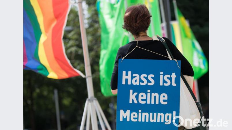 Eine Aktivistin der Nichtregierungsorganisation Campact steht mit einem Plakat mit der Aufschrift "Hass ist keine Meinung" am Eingang zum Landesparteitag von Bündnis 90/Die Grünen um gegen Hassnachrichten ("Hate Speech") im Internet zu protestieren. Bild: Frank Rumpenhorst/dpa