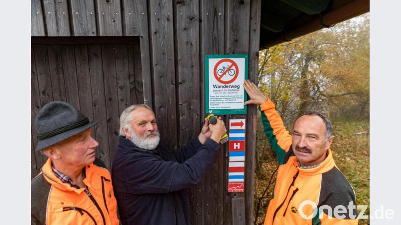 Revierleiter Hermann Kießling (links) und Winfried Pfahler, Leiter des Forstbetriebs Fichtelberg (rechts), montieren mit Christian Kreipe vom Fichtelgebirgsverein das Schild zur Besucherlenkung auf dem Wandersteig am Kösseinehaus. Bild: Martin Hertel/exb