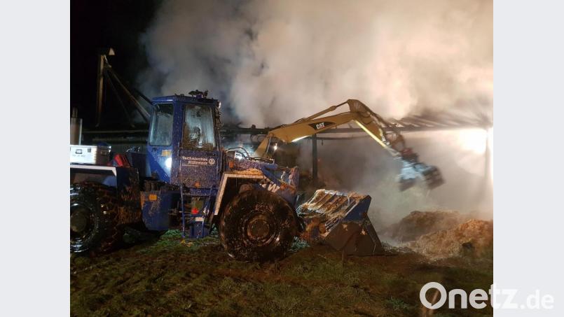 Die THW-Ortsgruppen Weiden und Schwandorf helfen in der Brandnacht am Mittwoch zusammen. Mit einem Mobilbagger und Radlader wird das brennende Stroh zur Seite geschoben. Bild: exb/Jan Braunreiter/THW