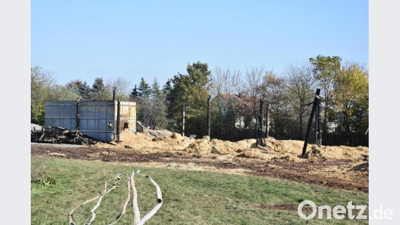 Vom Löschen liegen noch Schläuche auf der Wiese. Die Lagerhalle mit 450 Strohballen ist ausgebrannt. Nicht mehr zu gebrauchen sind auch die Blechsilos, in denen Getreide lagerte. Bild: Hladik