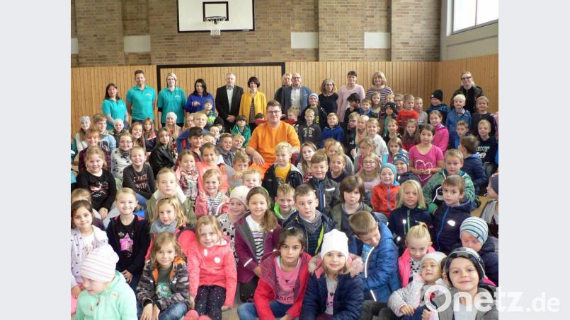 Mitten in der Schulfamilie - im Hintergrund Elternbeirat, Verwaltung und Lehrkräfte - nimmt der neue Hausmeister Lucas Lohner auf einem purpurroten Stuhl Platz. Seit 1. August kümmert er sich um die Belange der Schule. Bild: lep