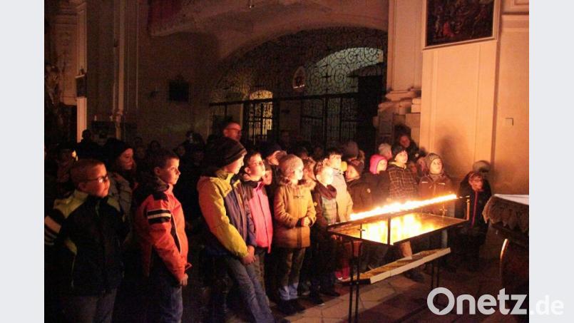 Die Teilnehmer bei den Opferkerzen, die den sonst dunklen Kirchenraum hell erleuchteten. Bild: Monika Demmer/exb
