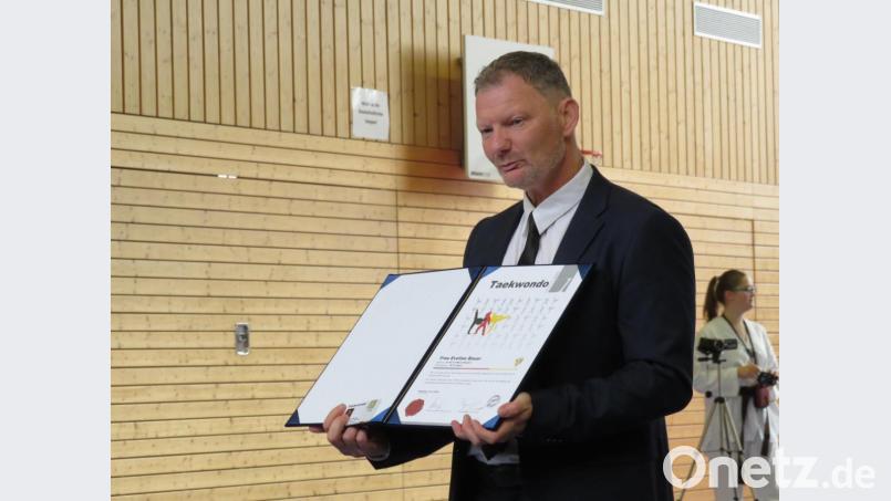 Prüfer Roland Hofbauer zeigt den Zuschauern die Urkunden und klärt die neuen Dan-Träger über ihre Pflichten und Rechte auf. Bild: adj