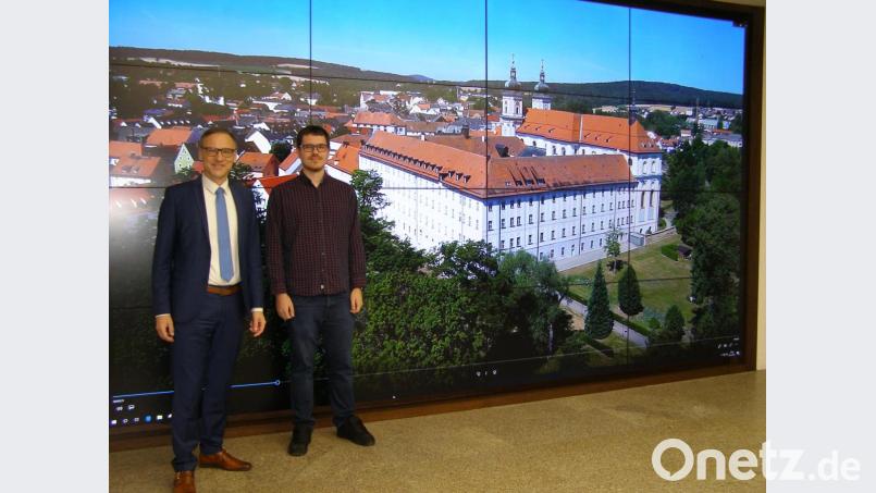Bürgermeister Bernd Sommer und Philip Werfl (von links) im Rathaus-Foyer vor der Videowand mit einer Szene aus dem Film. Bild: pz