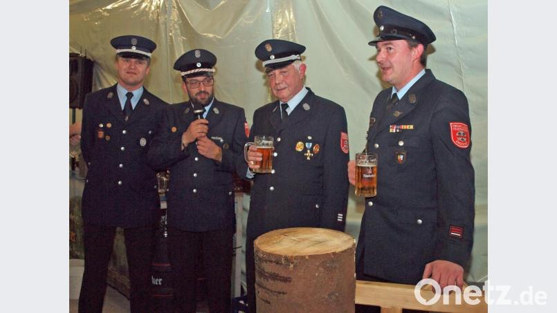 Der Baumstamm ist durchsägt. Kommandant Martin und Vorsitzender Richard Reiser Reiser haben ein Bier verdient, sind Thanheims Vorsitzender Marcus Färber und Kommandant Michael Rothut III. (von rechts) überzeugt Bild: sön