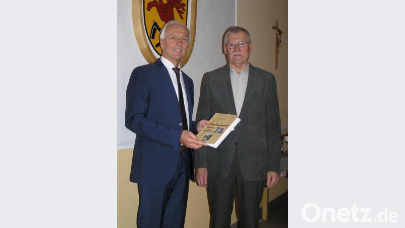 Autor Hans Enders (rechts) übergab bei seiner Buchvorstellung das erste Exemplar des Buches „Schwarzenreuth – Geschichte und Geschichten“ an Bürgermeister Peter König. Bild: öt