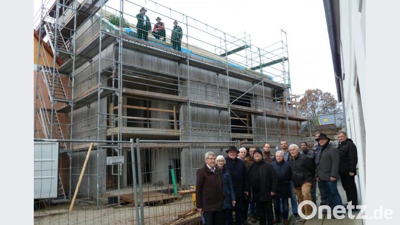 Während die Zimmerer auf den Einsatz für den Richtspruch warten, versammeln sich die geladenen Gäste um Bürgermeister Heinz Weigl (Dritter von links) und Architekten Peter Brückner (rechts daneben) vor dem imposanten Neubau. Bild: Portner