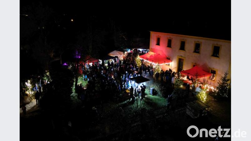 Die Buden leuchten im Garten zwischen den Kirchen, dazwischen tummeln sich zahlreiche Besucher. Rechts im Bild ist das evangelische Pfarrhaus. Bild: exb