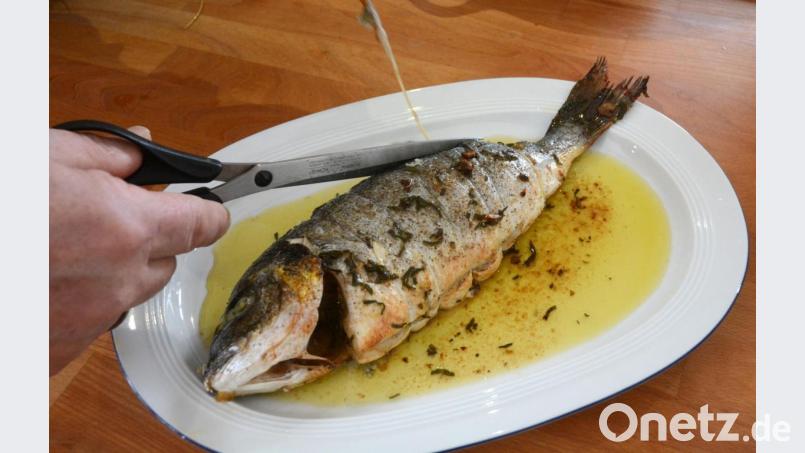 Nach dem Braten wird das Küchengarn von der Dorade entfernt. Bild: Gabi Schönberger