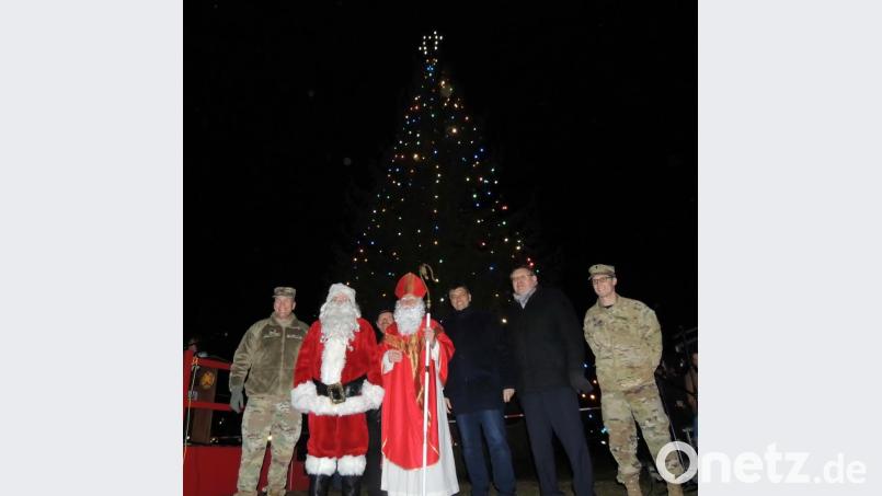Oberst Adam Boyd, Santa Claus, der Heilige Nikolaus, Helmut Amschler vom DAGA, die Bürgermeister Edgar Knobloch und Hans Martin Schertl sowie Chaplain Joshua Giliam (von links) läuten vor dem beleuchteten Weihnachtsbaum die Weihnachtszeit ein. Bild: mor