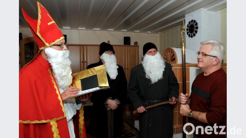 Natürlich muss Hans Sturm (rechts) keinen Tadel fürchten, wenn der Nikolaus zu ihm kommt und sein goldenes Buch aufschlägt. Stadtpfarrer Thomas Helm (links), der für den seit 50 Jahren in diese Rolle schlüpfenden Diener seiner Pfarrei selbst das Gewand des Heiligen angelegt hatte, wusste nur Bestes zu berichten. Und die beiden Knechte Ruprecht durften ihre Rute auch getrost stecken lassen. Bild: Stephan Huber
