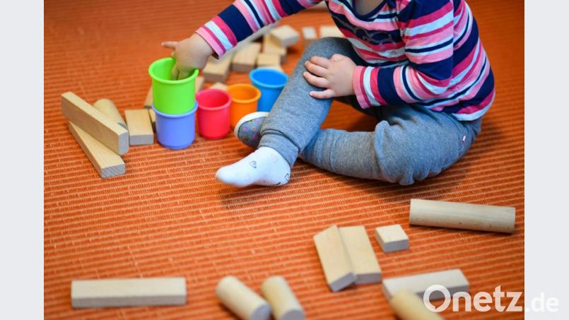 Symbolbild: Ein Mädchen spielt in einer Kita mit bunten Bechern und Bauklötzen. Bild: Uwe Anspach/dpa