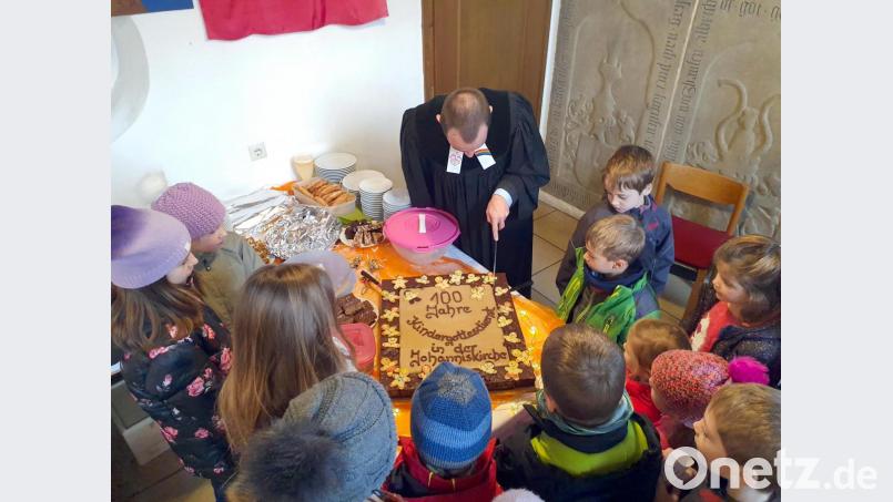 Pfarrer Hartmut Klausfelder schneidet den Geburtstagskuchen an, der von Kindern und Festgästen sofort aufgegessen wird. Bild: gac