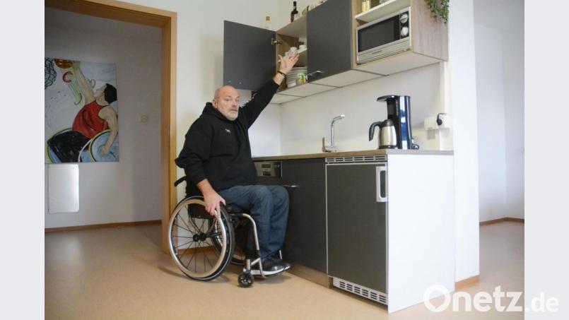 Stefan Kessler demonstriert an einer Küchenzeile, dass die bei Aldi vergleichbar hoch montierten Kühlschränke für Rollstuhlfahrer nicht mehr zu erreichen sind. Bild: Gabi Schönberger