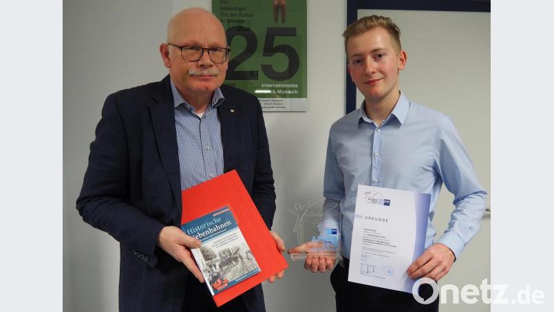 Stolz präsentiert Lukas Dausch als deutschlandweit bester Azubi im Güterzugbereich seine Auszeichnungen. Vom Leiter DB Cargo Nordostbayern erhält er ein Buchgeschenk. Bild: Bühner