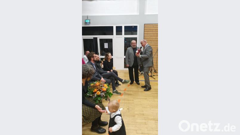 Bürgermeister Roland Strehl übergibt an Heinz Lang das Präsent der Gemeinde. Links im Bild die Familie von Lang. Bild: kal