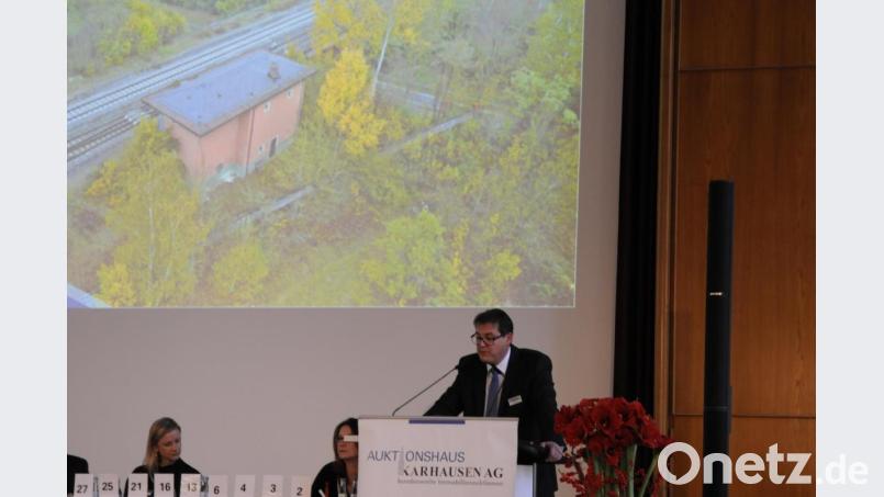 Auktionator René Silva (am Pult) gab für das Vilsecker Stellwerk (im Hintergrund als Luftbildaufnahme) dem einzigen Angebot in Höhe von 5000 Euro den Zuschlag. Bild: Ingmar Höfgen
