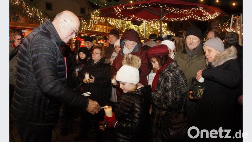 Dekan Hans Amann (links) reichte das Friedenslicht weiter an die Besucher des Weihnachtsmarktes. Bild: Hirsch