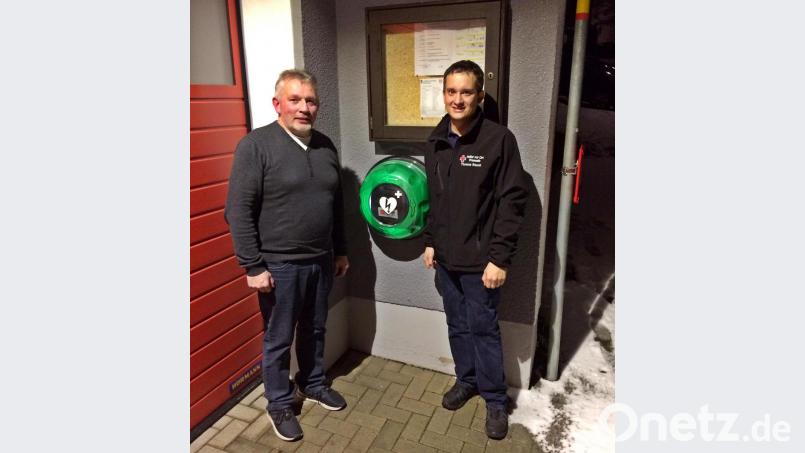 Über den neuen Defibrillator am Friedersreuther Feuerwehrgerätehaus freuen sich Wehrsvorsitzender Siegfried Steiner (links) und Thomas Rauch vom Pressather BRK-Ortsverband. Bild: jma