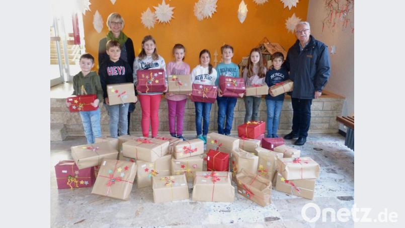 Stolz übergeben die Kinder der Grundschule Teunz gemeinsam mit Schulleiterin Friederike Bösl die Päckchen für die Oberviechtacher Tafel an Dr. Friedrich Keller. Bild: weu