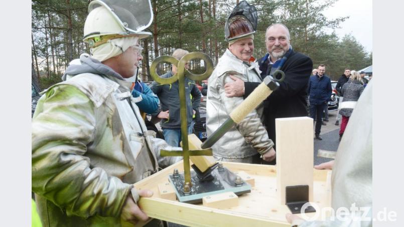 Der Manager Reinhold Gietl (vorne, rechts) ist einer von ihnen: Produktionsmitarbeiter überreichen ihm zum Abschied ein geschmiedetes Glasmacherkreuz, einen Hammer und ein Stück Gestein aus dem Bassin einer Schmelzwanne. Bild: Gabi Schönberger