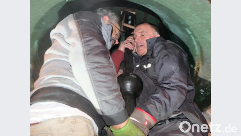 Eng geht es zu unter der Glocke, als der Klöppel einzuhängen ist. Pfarrrer Heinrich Rosner und Peter Irlbacher haben es sich nicht nehmen lassen, bei der schweren Arbeit selbst mit Hand anzulegen. Bild: mab